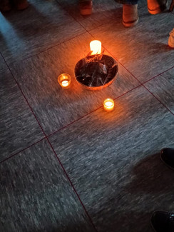 Schale mit Federn und Steinen und Kerzen darum